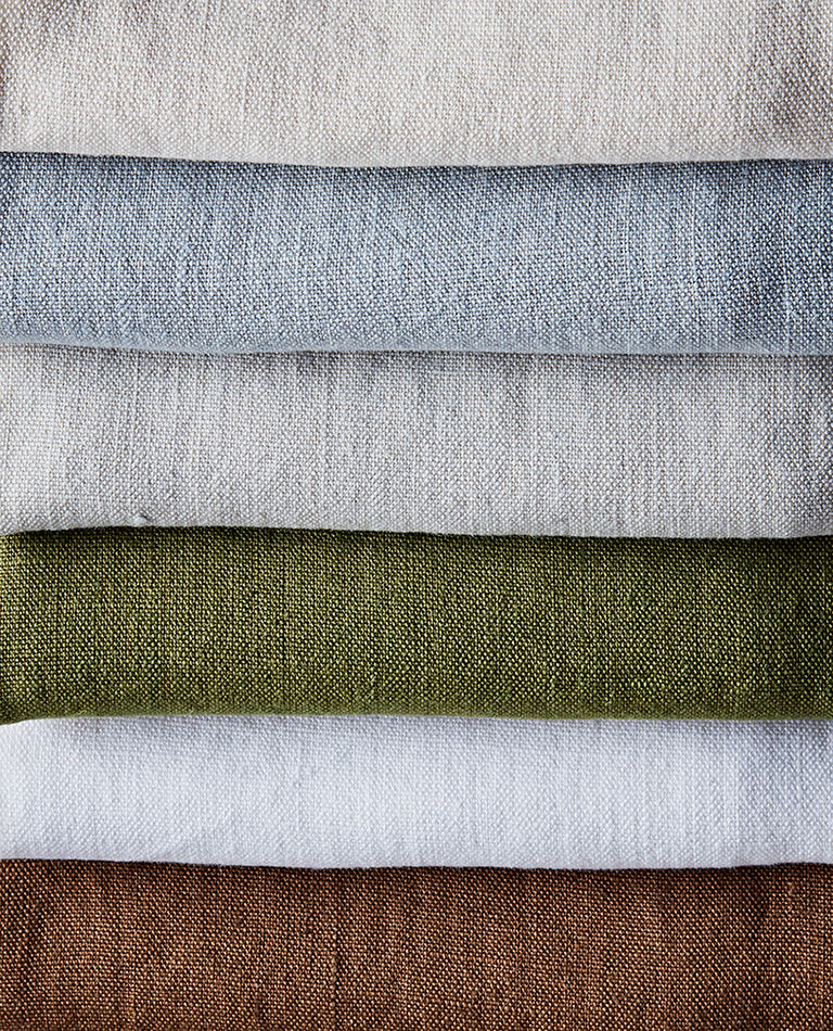 Stack of fabric swatches in various colors including gray, green, white, and brown.