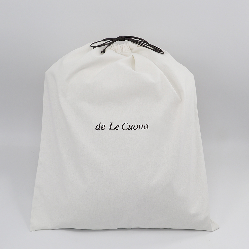 White drawstring bag with 'de Le Cuona' branding on a gray background