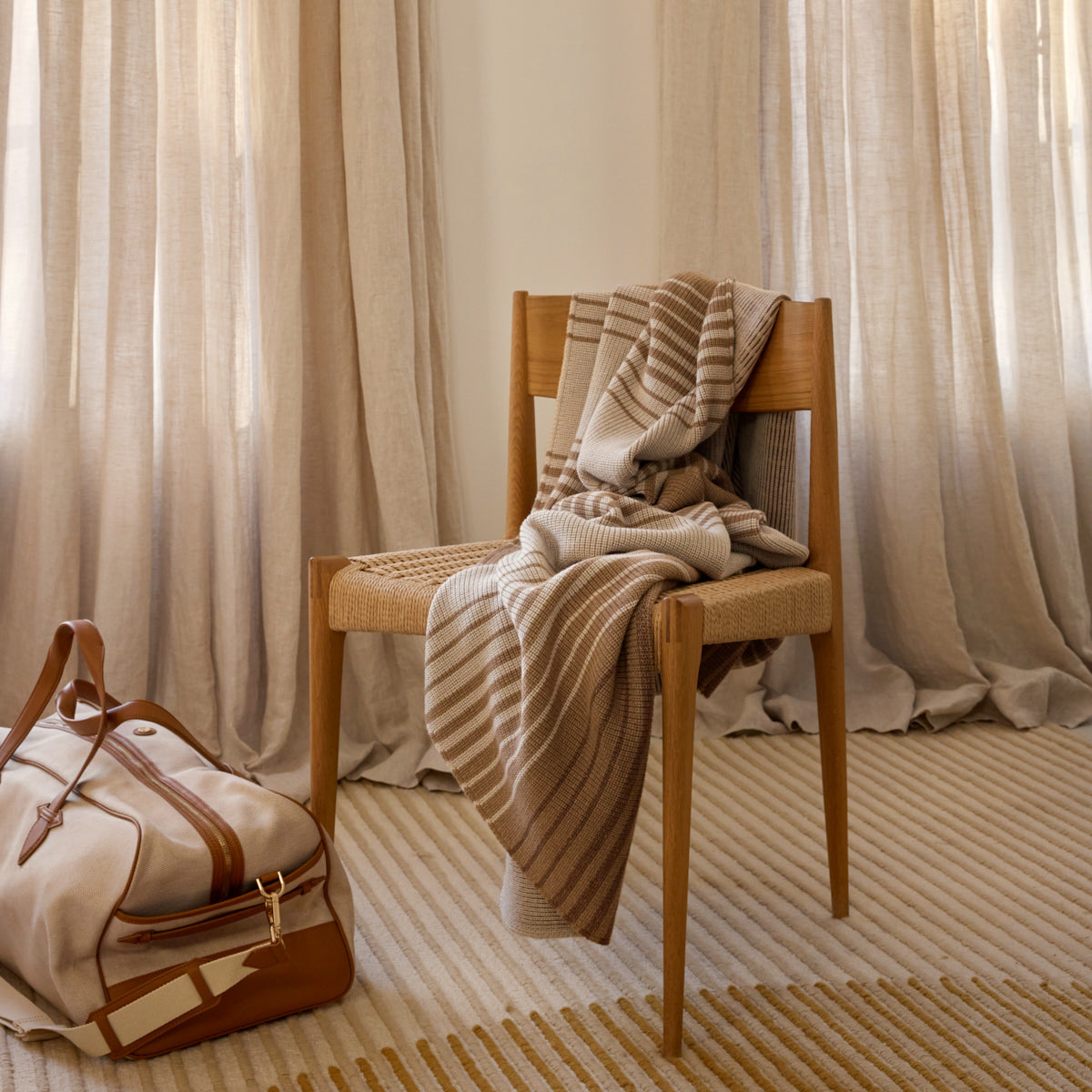Wooden chair with a blanket draped over it against a curtain backdrop
