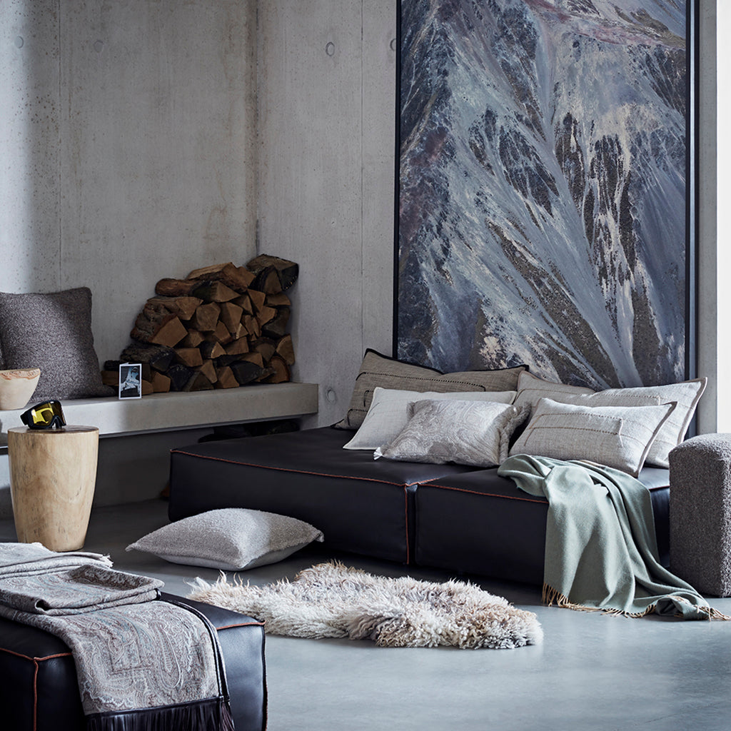 Modern living room with a dark brown sectional sofa, gray cushions, and a large abstract painting on the wall.