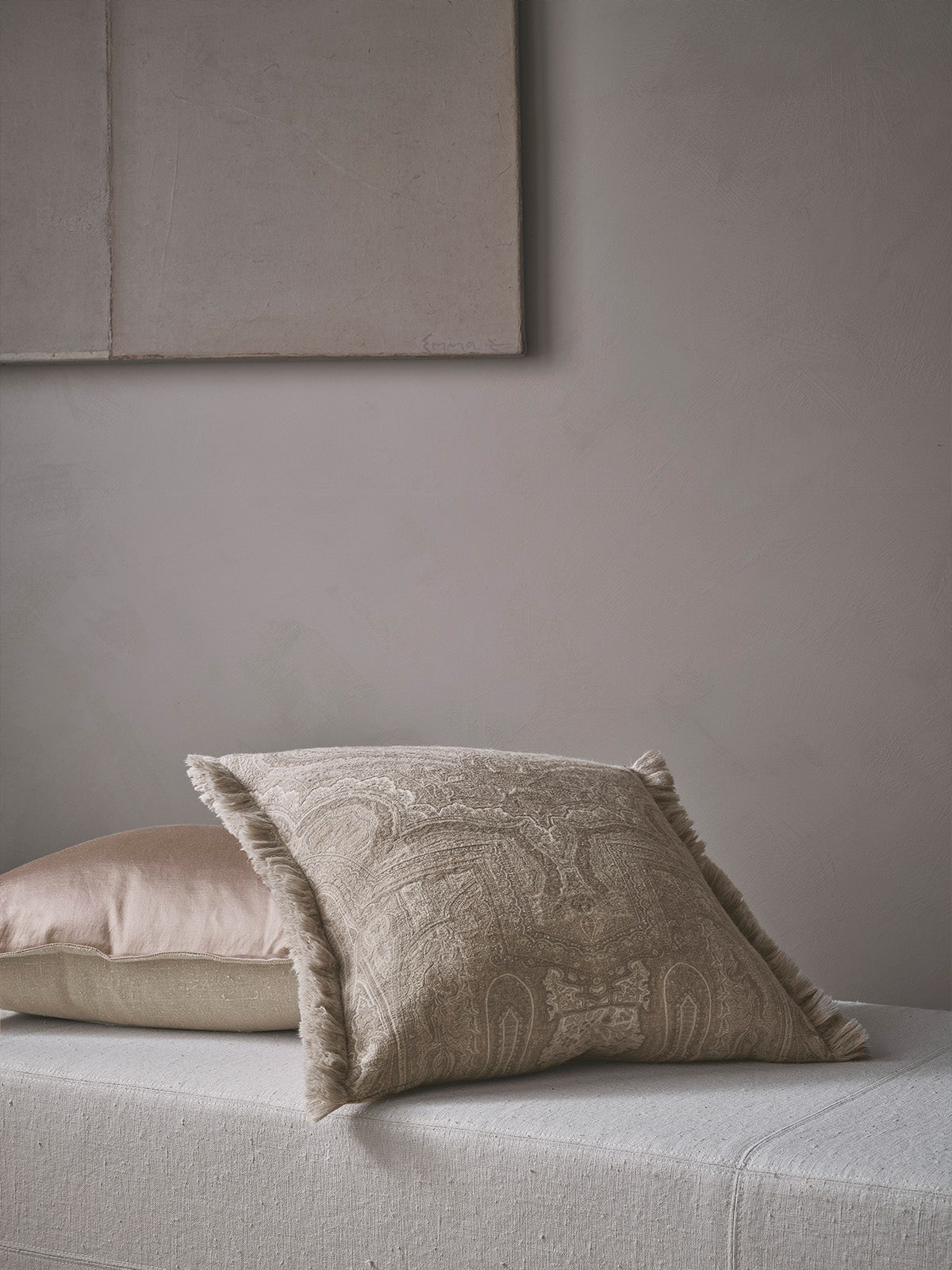 Textured beige pillow on a light gray sofa against a neutral wall.