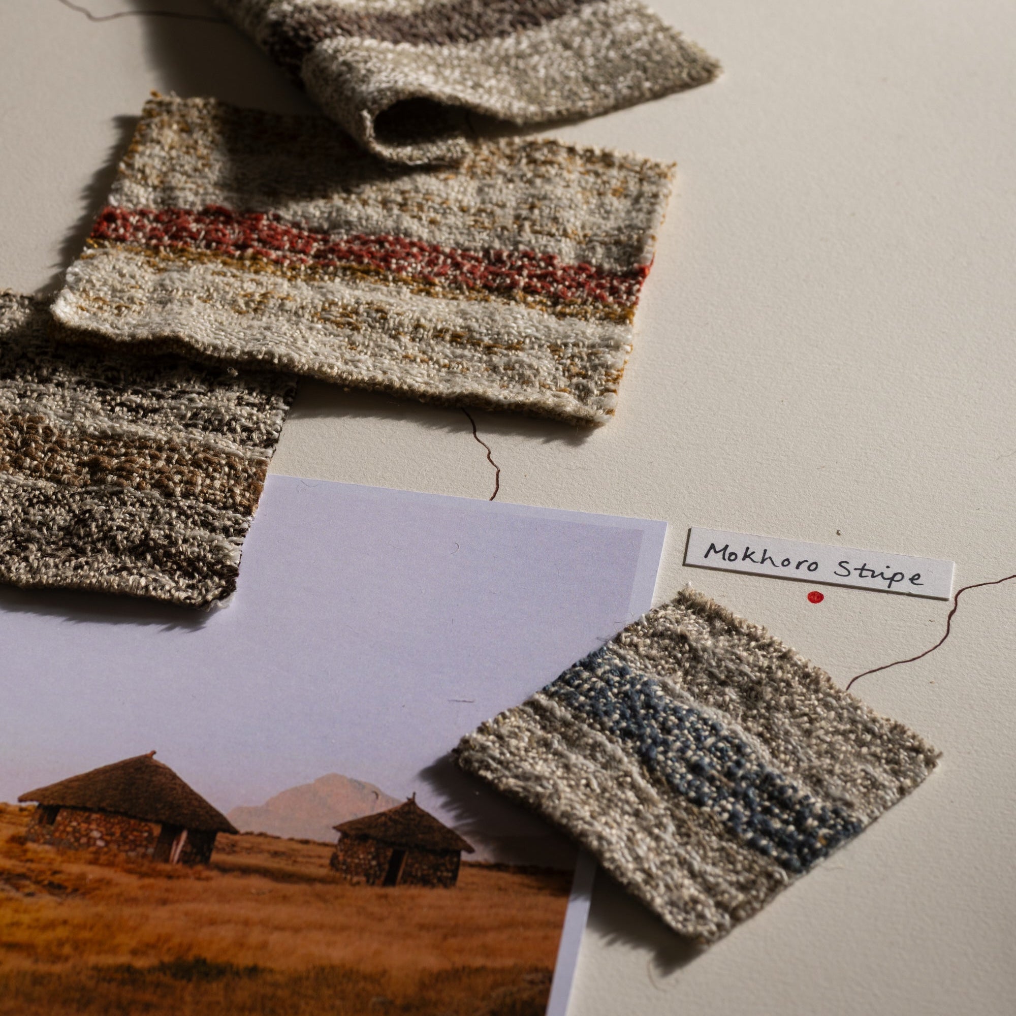 Textured fabric swatches on a surface with a landscape photo and label.