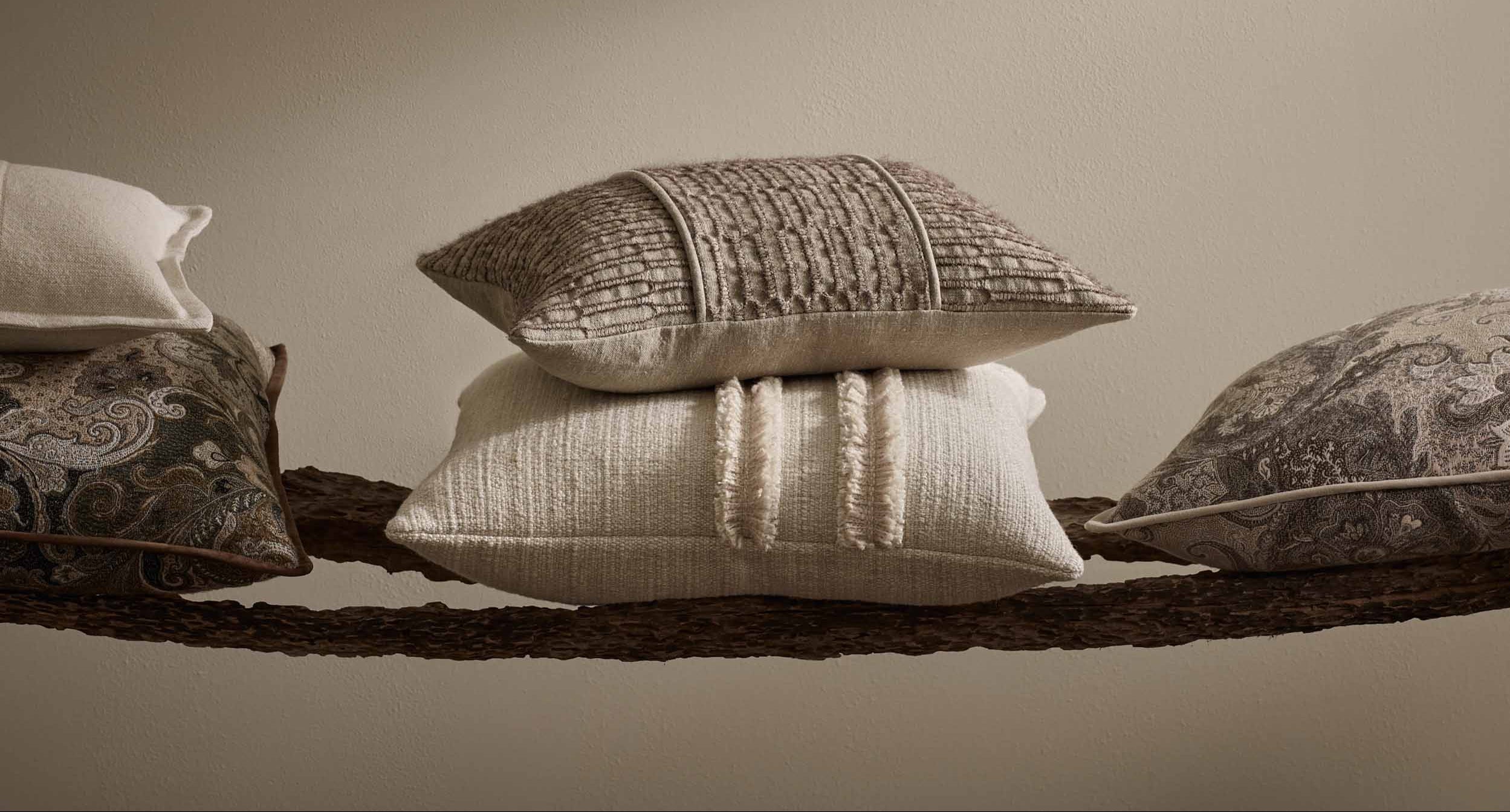 Stack of decorative pillows on a textured surface with a neutral background